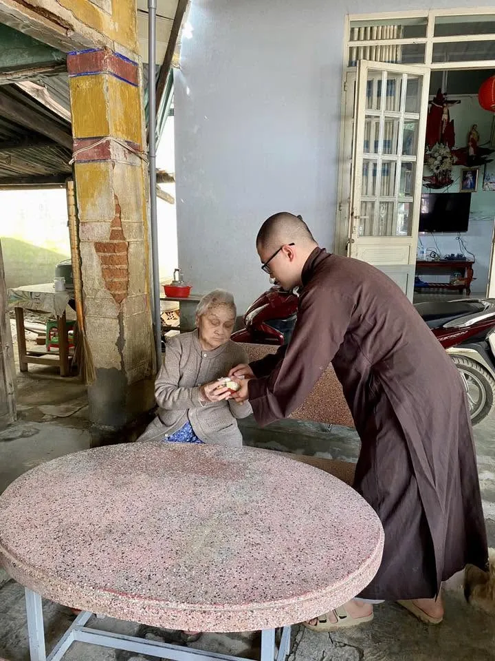 一位法师弯腰把礼物交给一位坐着的老奶奶