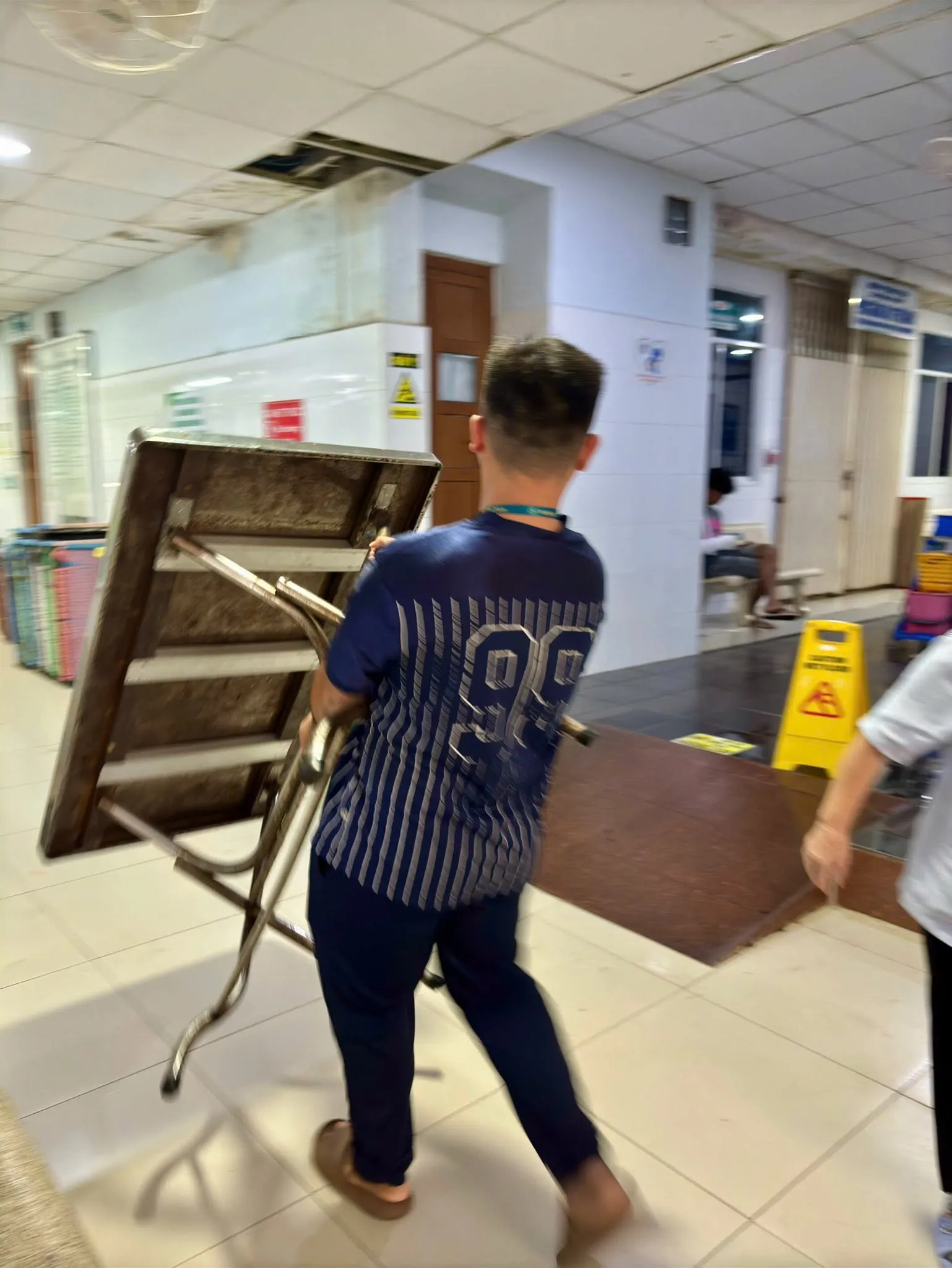 A volunteer carrying a folding table along the hospital corridor