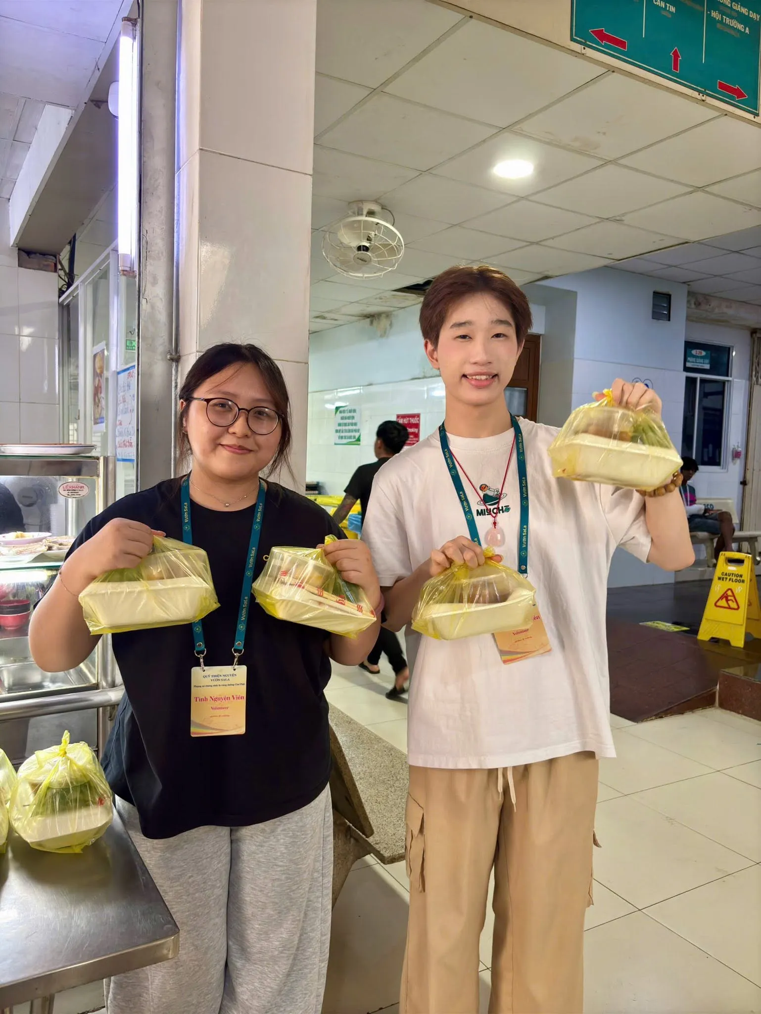 Two smiling volunteers holding up meal packs