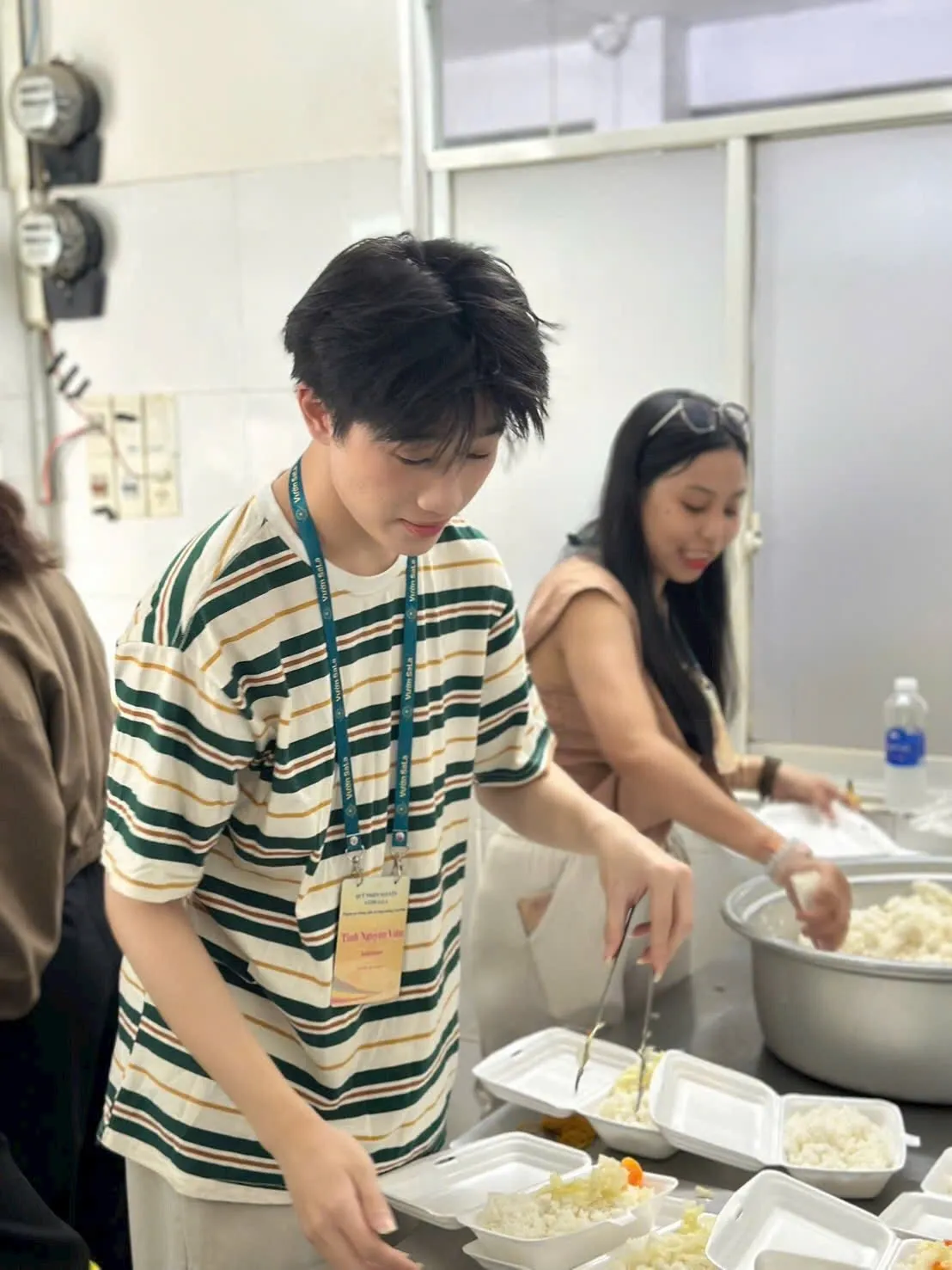 Các bạn tình nguyện viên dùng kẹp gắp thức ăn vào từng hộp cơm