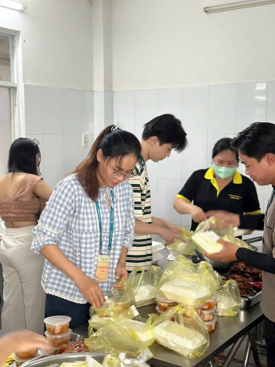 Các bạn tình nguyện viên cho hộp cơm và hộp nhựa nhỏ vào túi để đóng gói từng phần ăn
