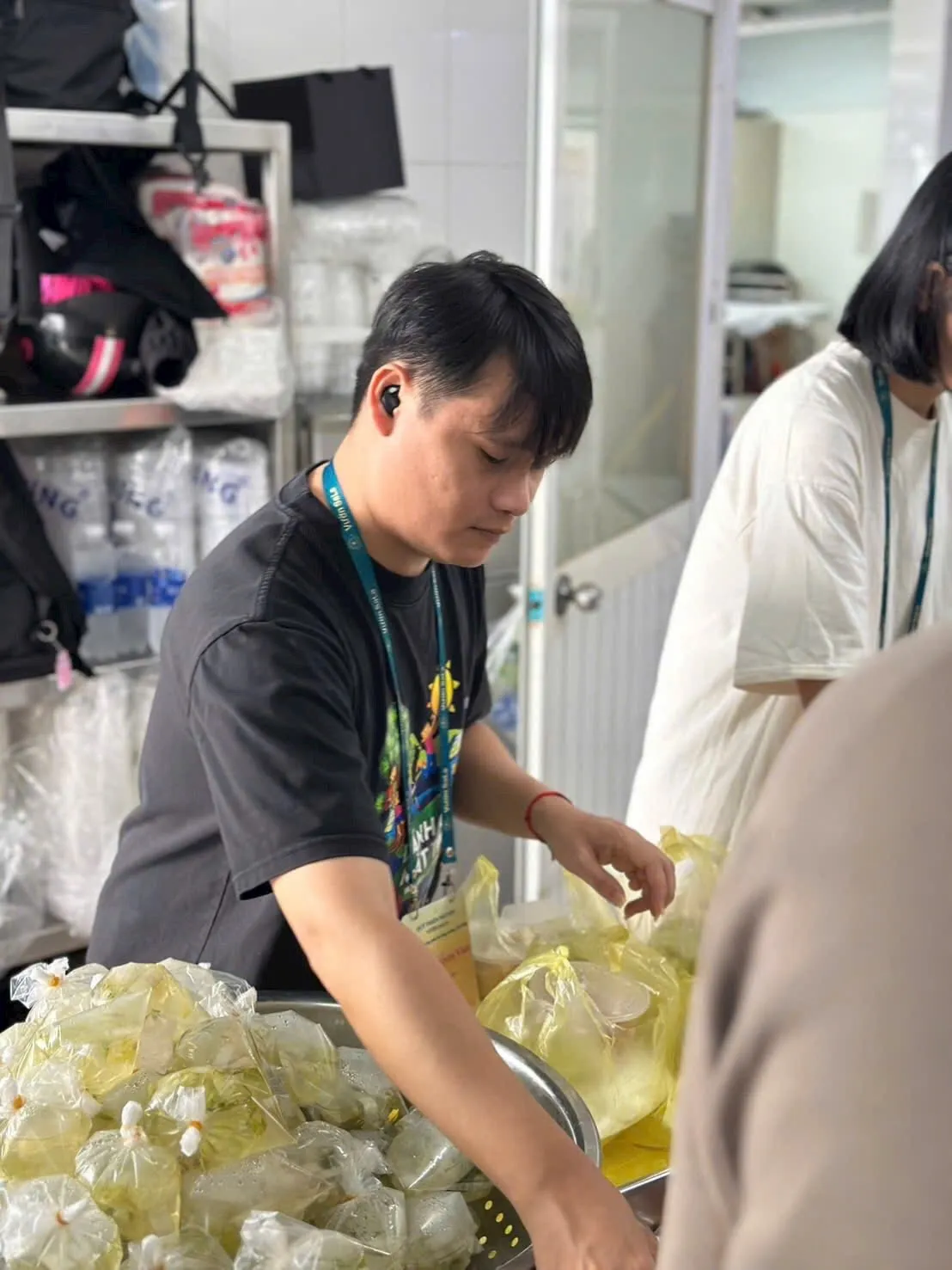 Một bạn tình nguyện viên bên thau đầy những phần cơm đã đóng túi