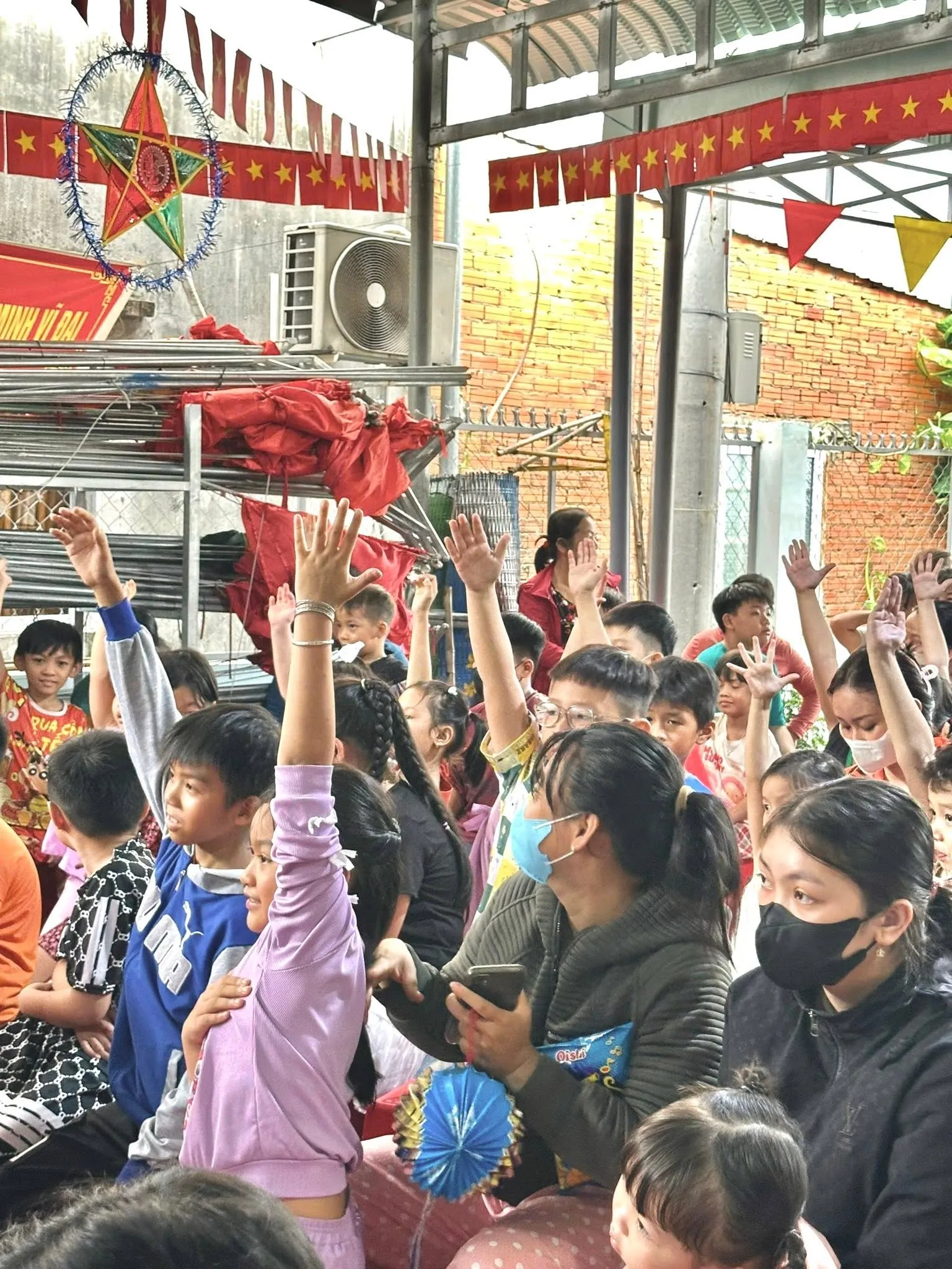 孩子们坐满了院子，许多孩子兴奋地举手参与活动