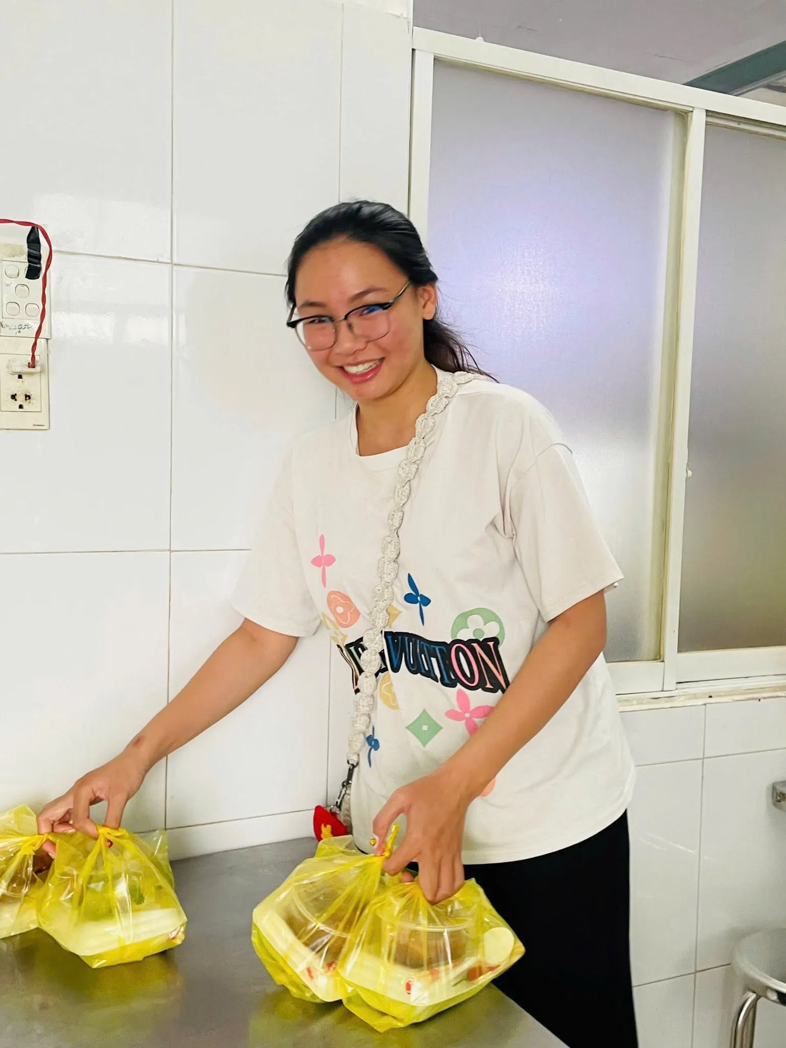 一位志愿者面带笑容地把袋装餐食放到桌上