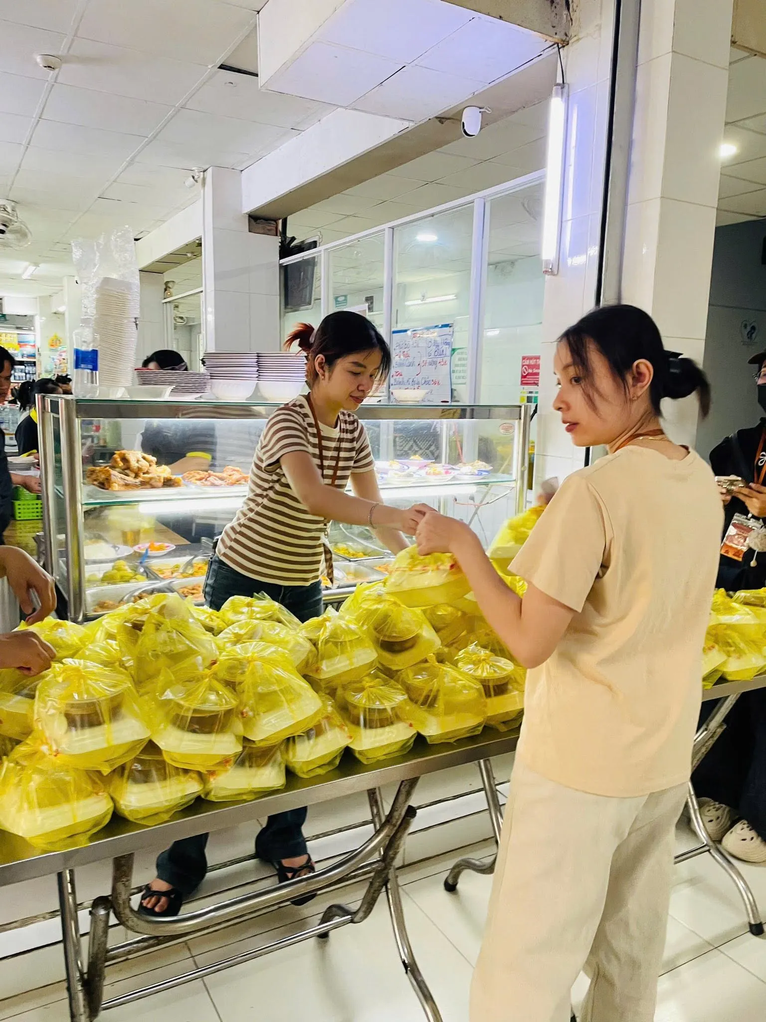 志愿者们在食堂摆满袋装餐食的桌旁