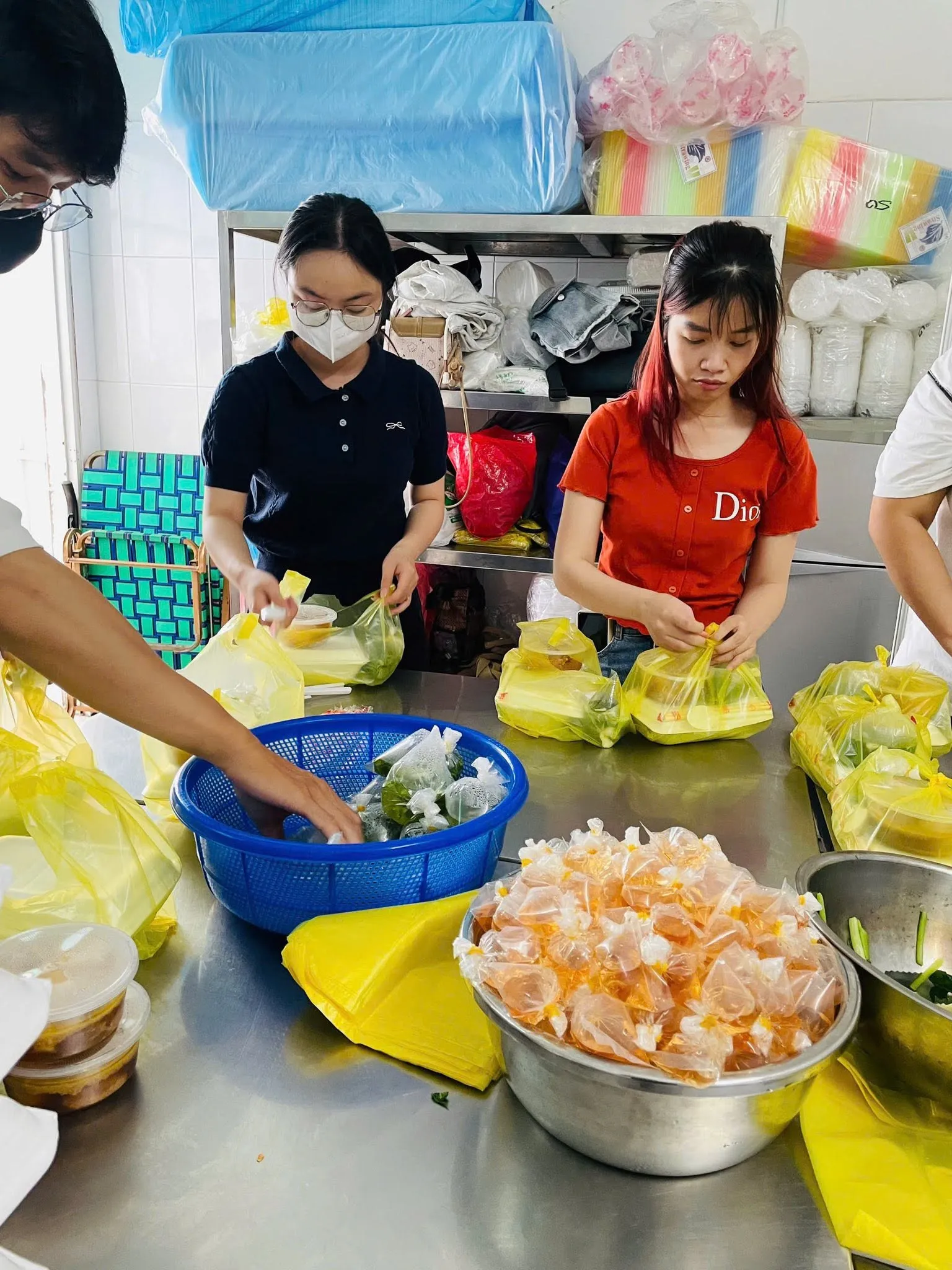 志愿者们在不锈钢台前把食物分装进袋子