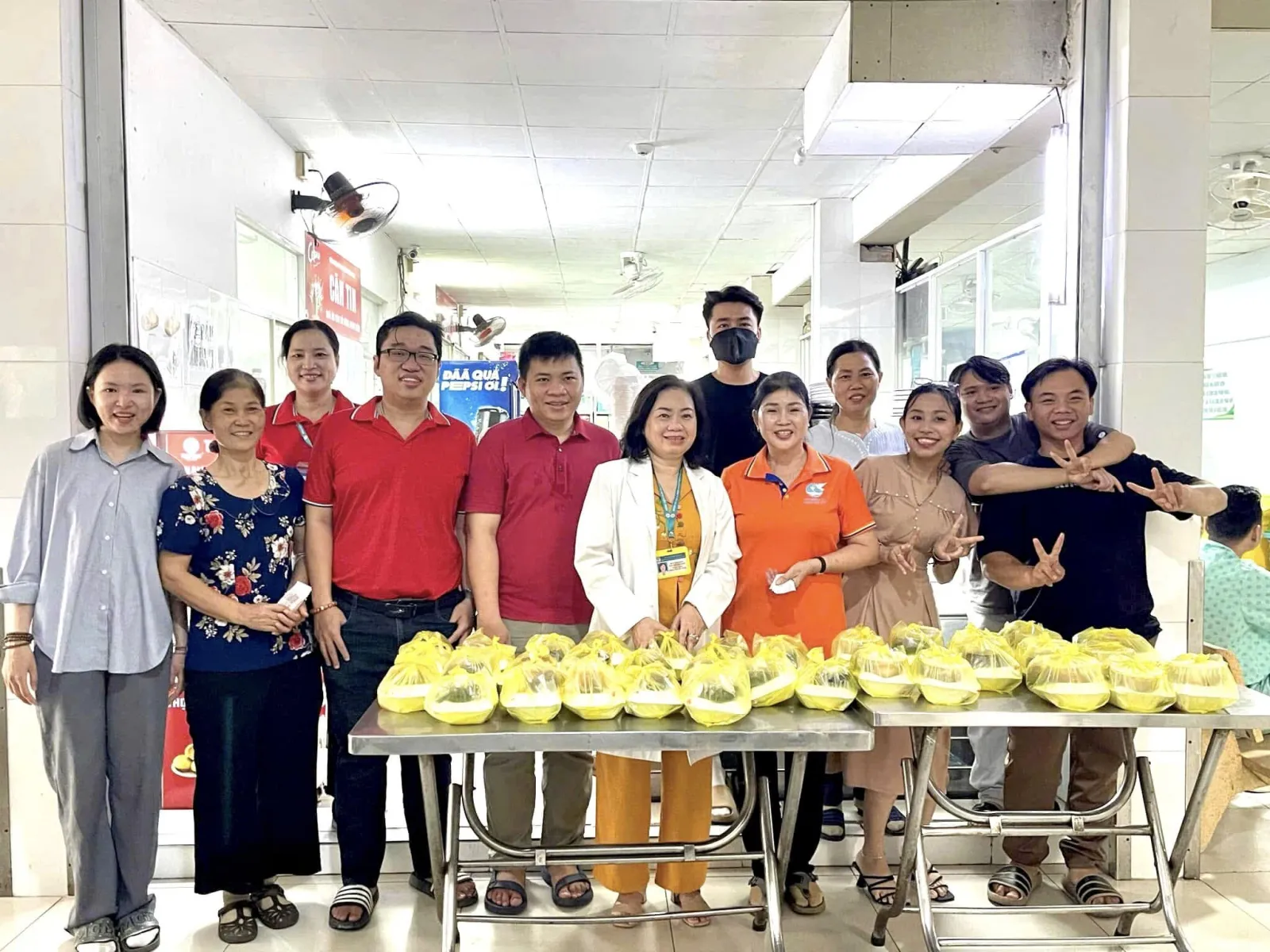 The volunteers in a group photo by two tables lined with packed lunches in the hospital canteen