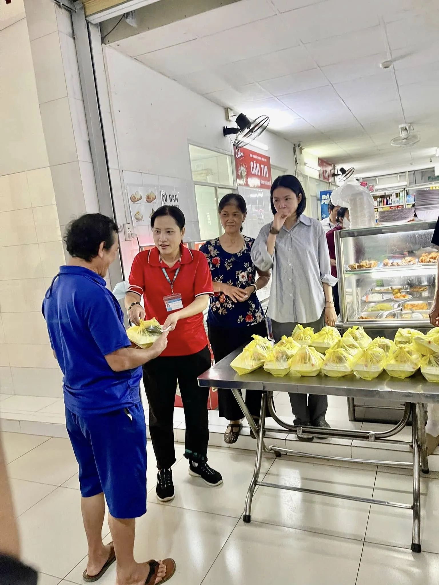A volunteer handing a lunch to a man in front of the canteen counter