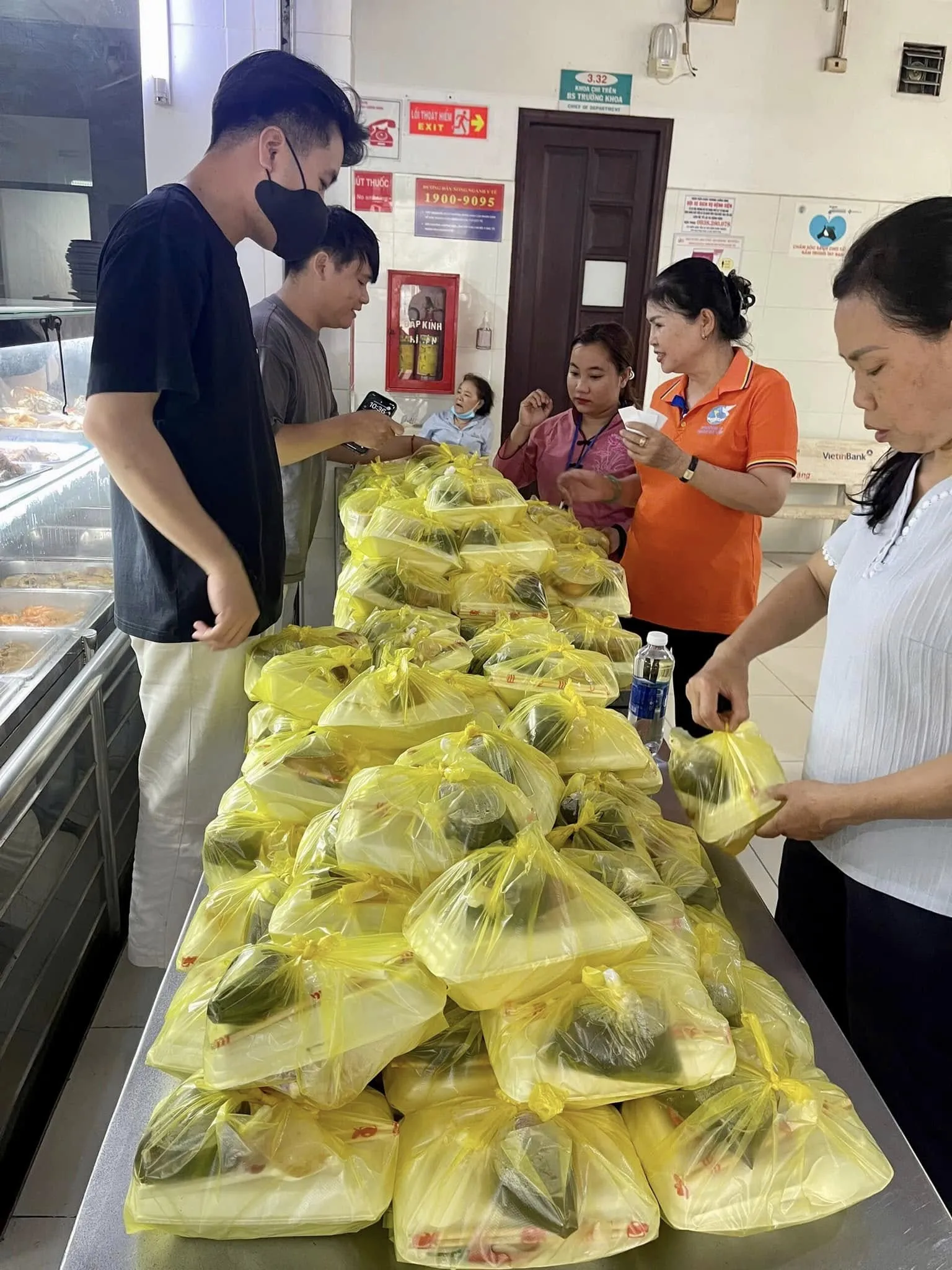 Volunteers standing by a table piled with meals, ready to hand them out