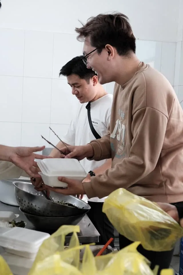 志愿者们在菜锅旁传递饭盒