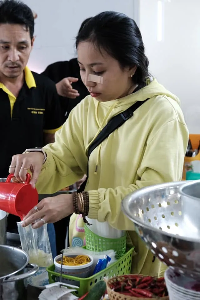 一位志愿者用红色塑料壶把汤水倒进袋子