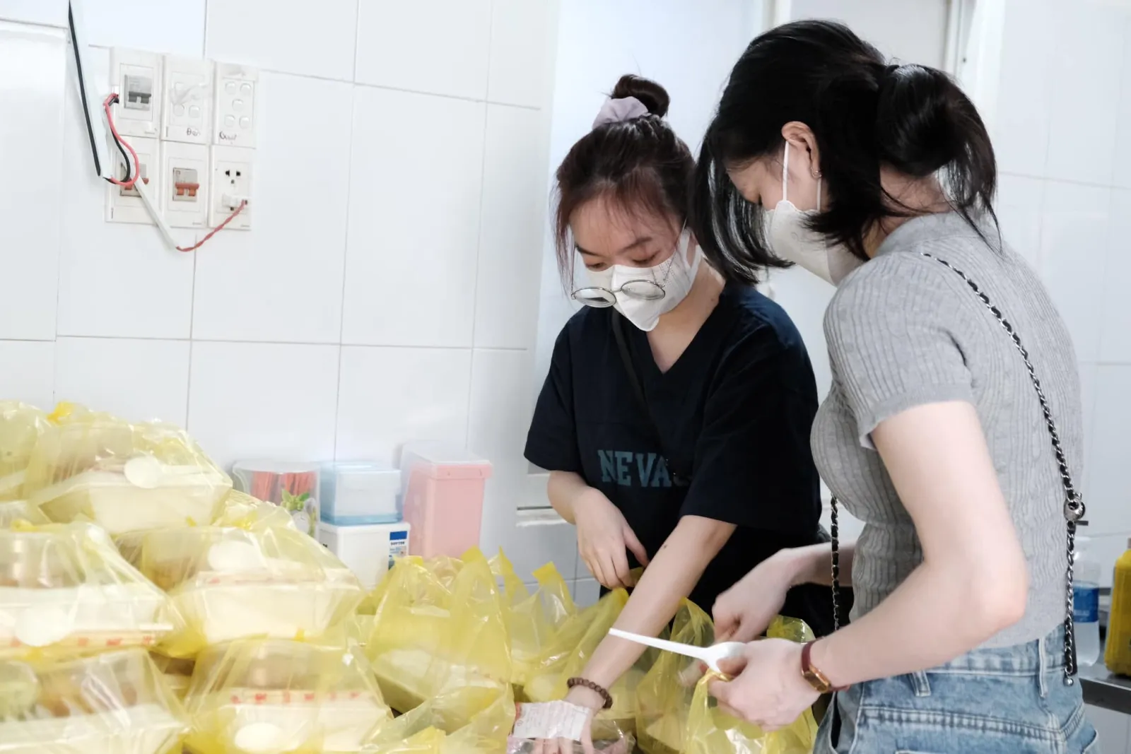 两位志愿者系好黄色的餐袋