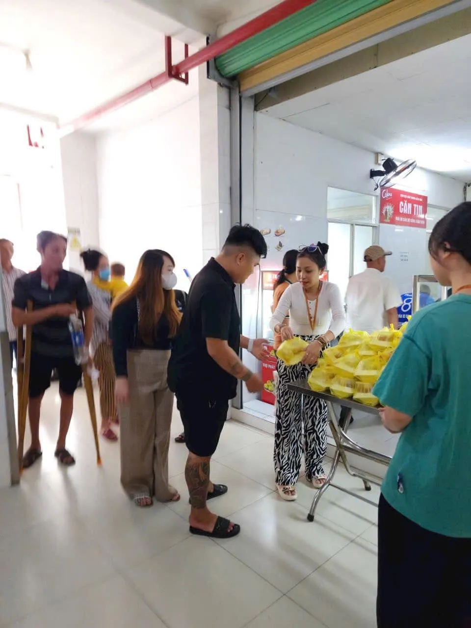 人们前来医院食堂前领取午餐,其中一人拄着拐杖