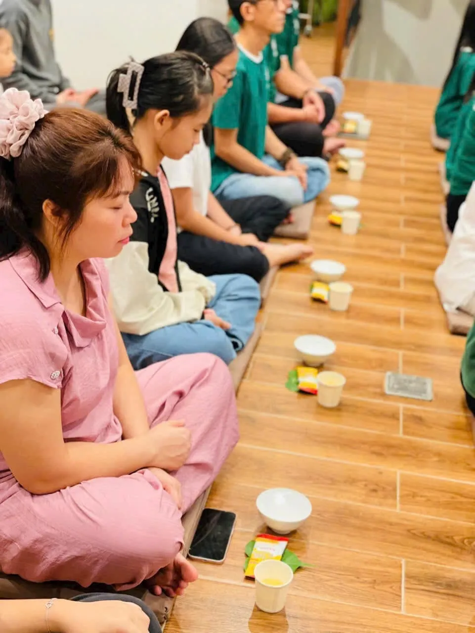 Người tham dự ngồi thành hàng dọc sàn gỗ, trước mặt mỗi người là chén trà