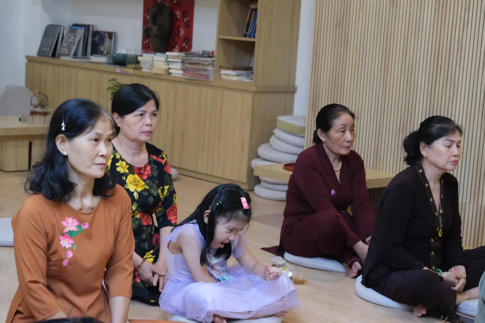Elders and a little girl sitting on cushions during the anniversary