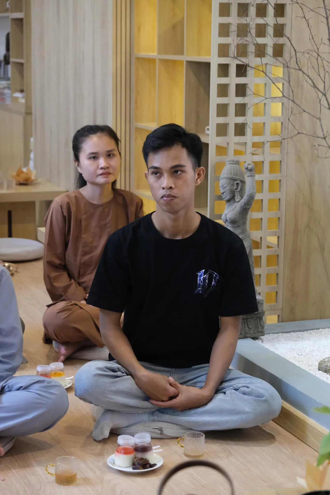 Two young people sitting and listening, with tea and snacks in front of them