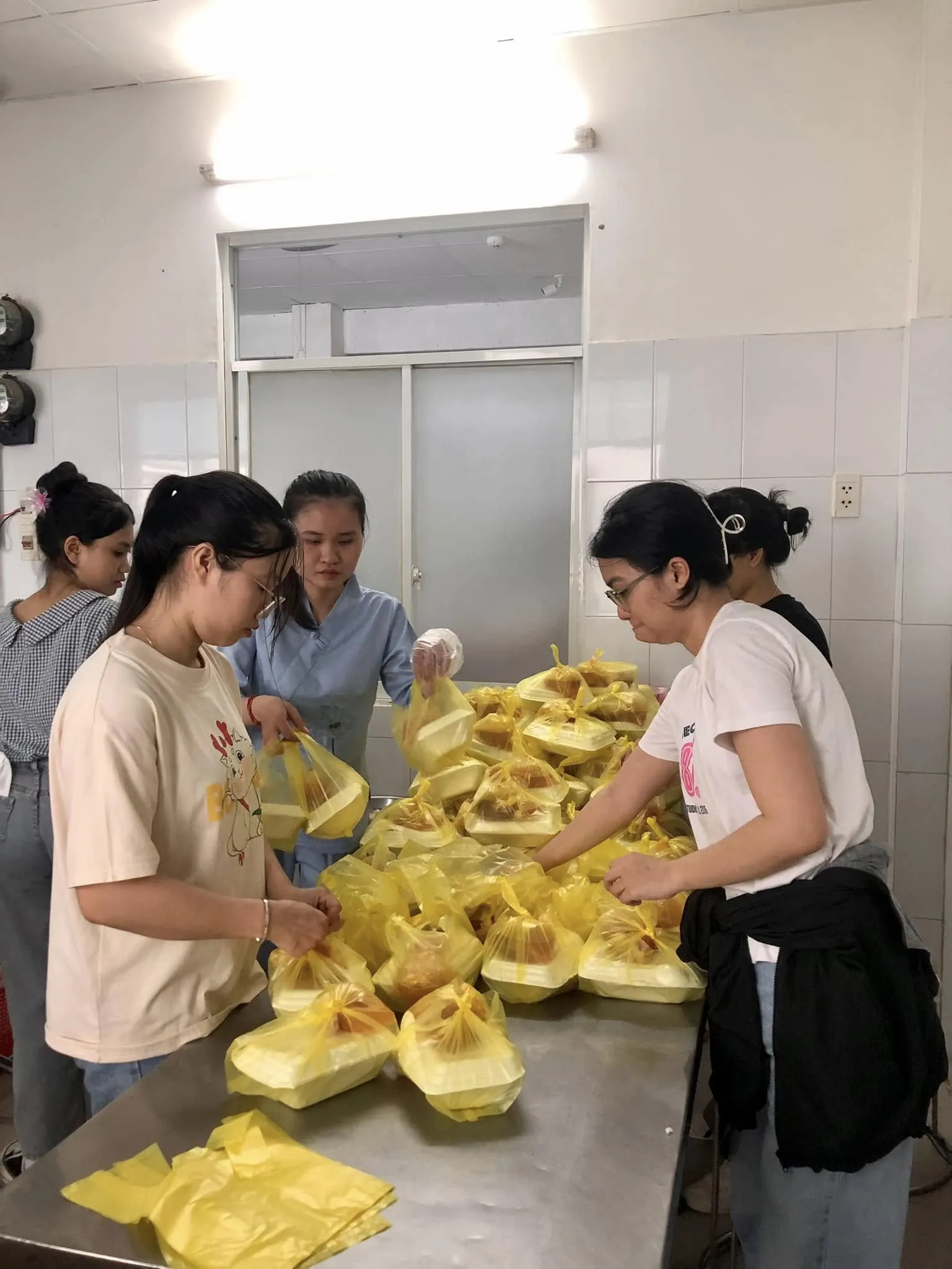 志愿者们在不锈钢台上把每个饭盒装进黄色袋子