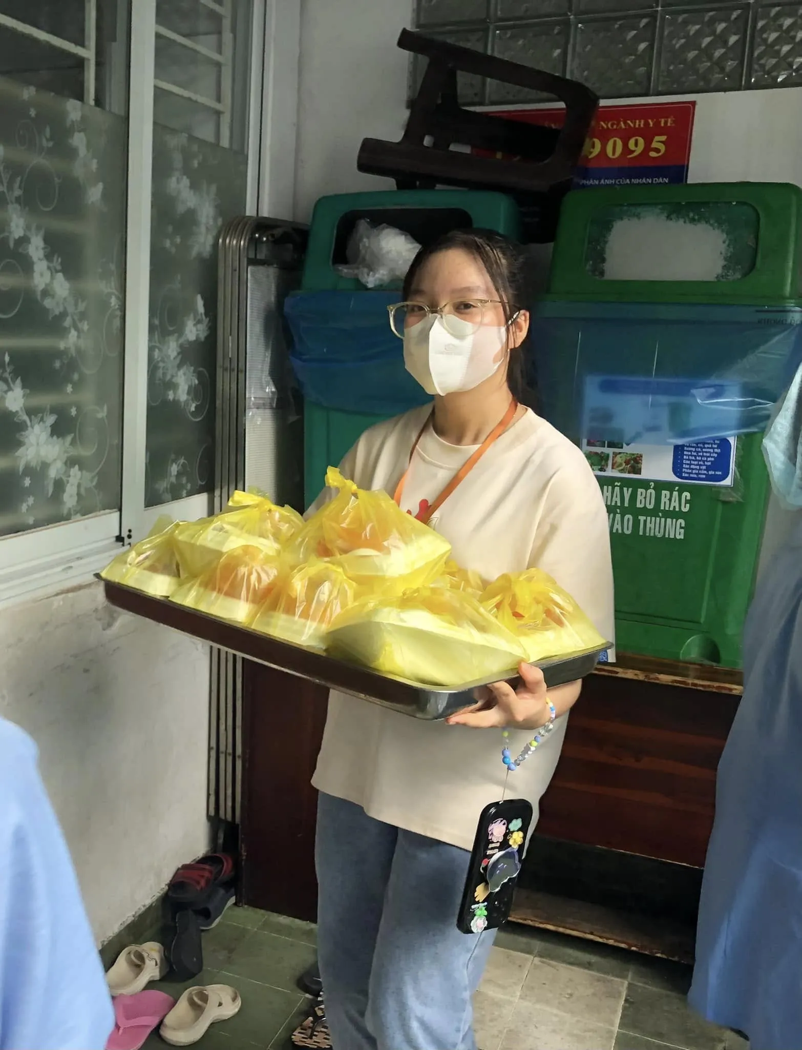 一位志愿者端着满满一托盘的餐袋