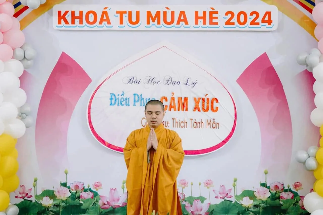 Vị giảng sư chắp tay trước phông chữ Khóa tu mùa hè 2024, bài học đạo lý Điều phục cảm xúc