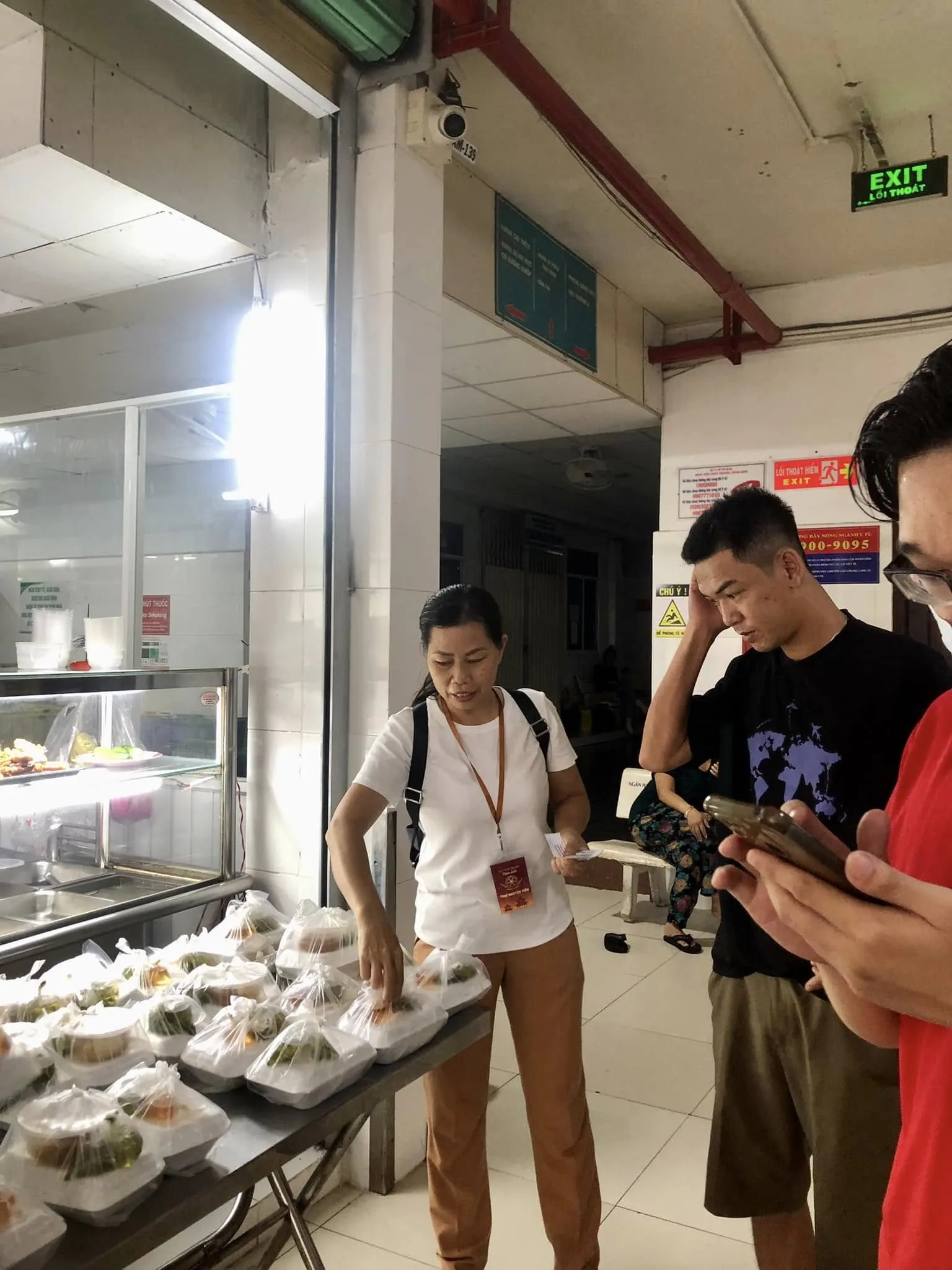 人们在医院走廊的桌旁前来领取餐食