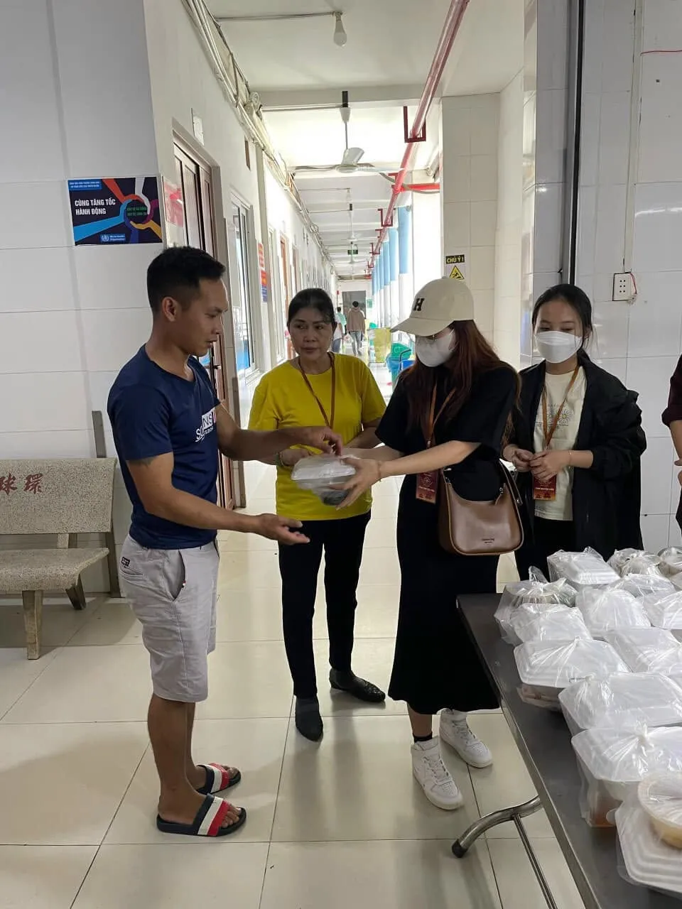 志愿者们把餐食递给一位身穿蓝色上衣的男士