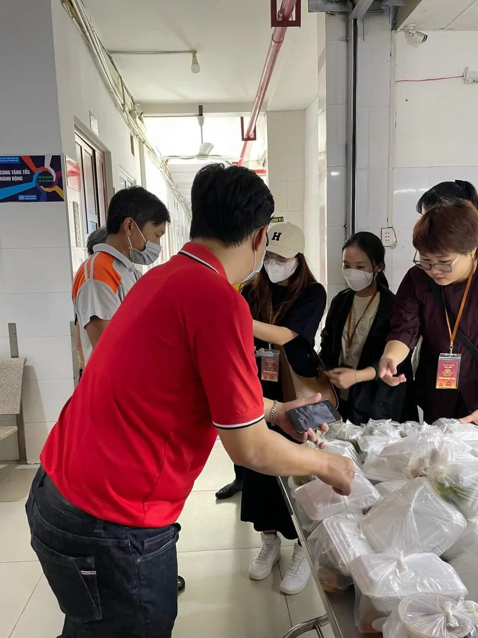 志愿者们在摆满餐袋的桌旁向人们分发餐食