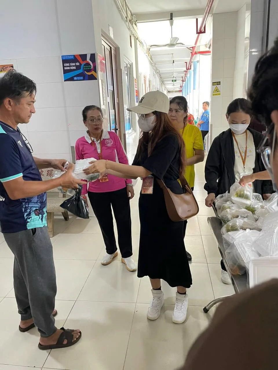 人们在医院走廊从志愿者手中领取餐食