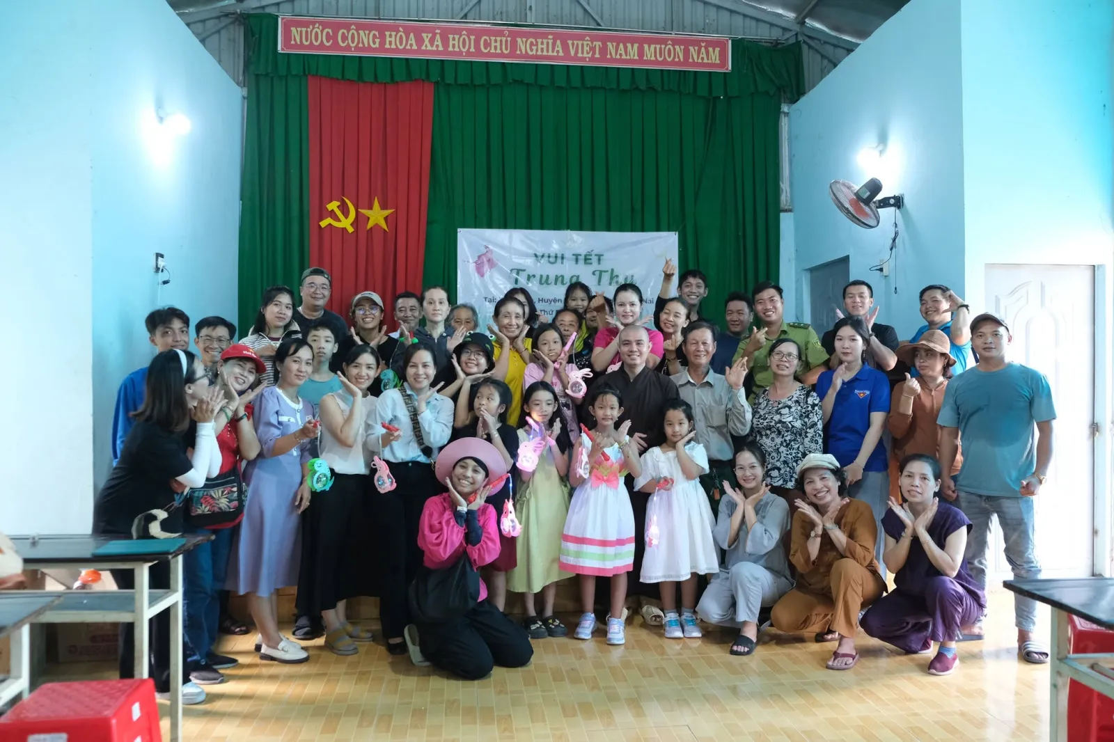 Ảnh chụp chung của đoàn và bà con địa phương trước phông chữ Vui Tết Trung Thu trong hội trường