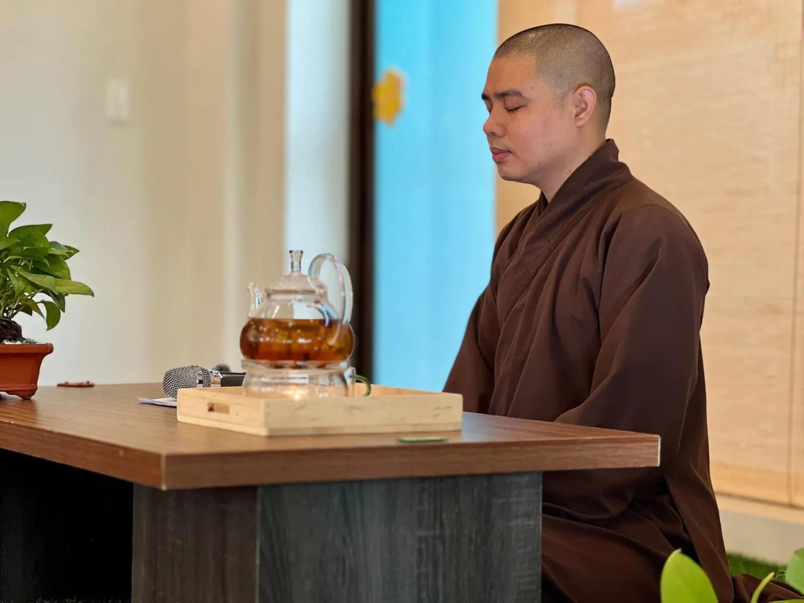 Thầy ngồi thiền, mắt khép lại bên bàn trà