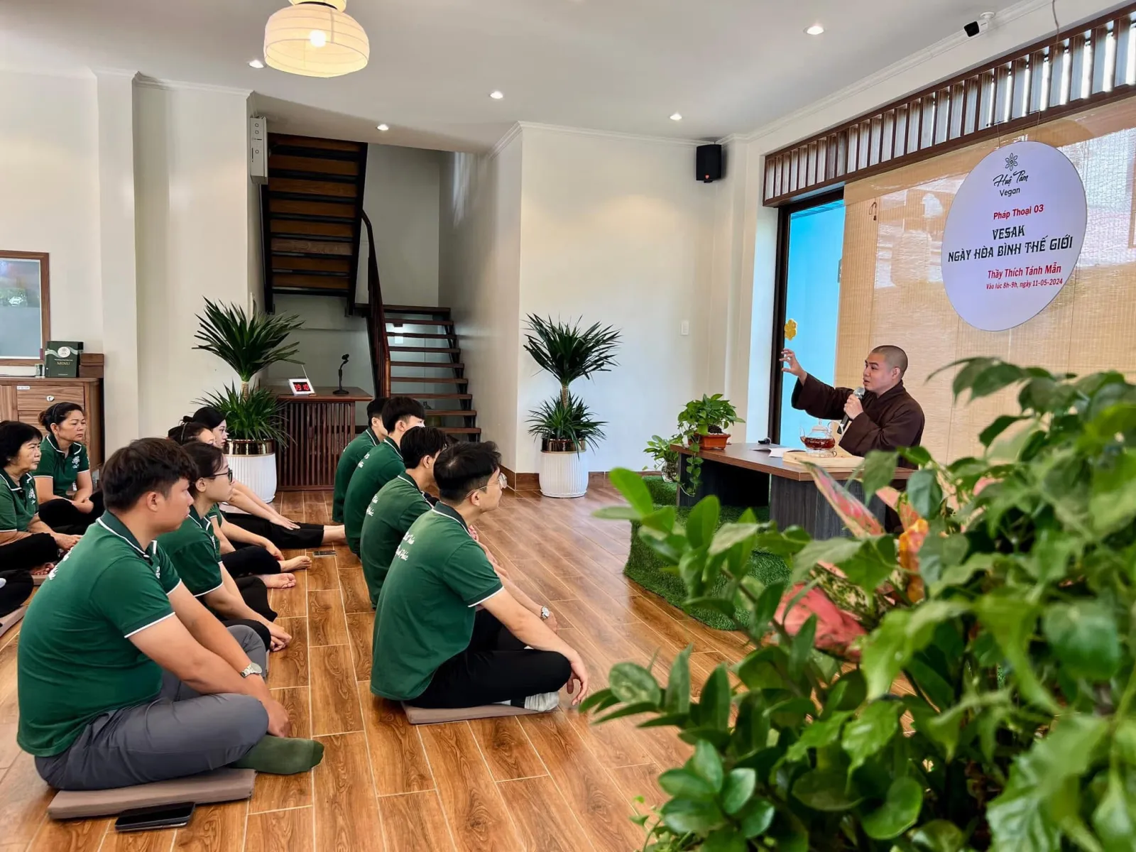 Thầy giảng pháp dưới bảng tròn Pháp Thoại 03, người nghe mặc áo xanh ngồi trên bồ đoàn lắng nghe